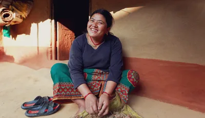 A smiling tribal woman posing for camera at her cosy village home